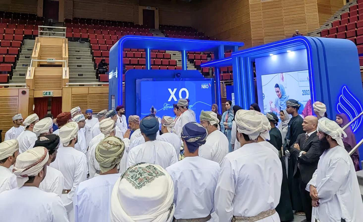 Large crowd of visitors gathered around the NBO exhibition booth featuring the XWall interactive gaming screen at a trade show.